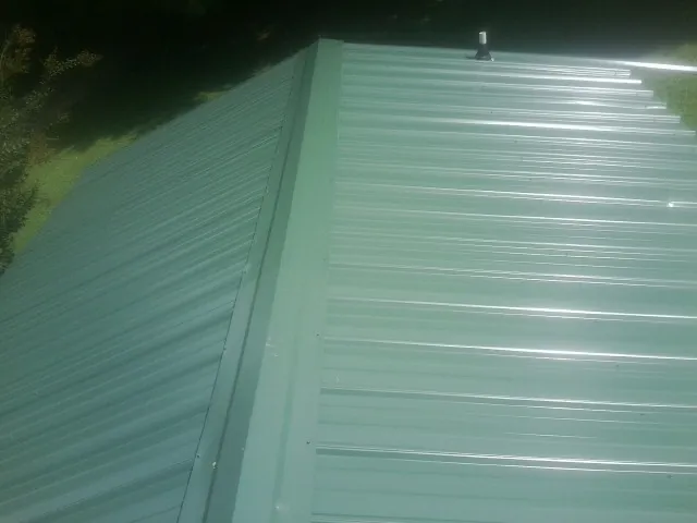 New green metal panels meeting at the ridge of a roof — Flat Roof Repair work by our crew in Finley