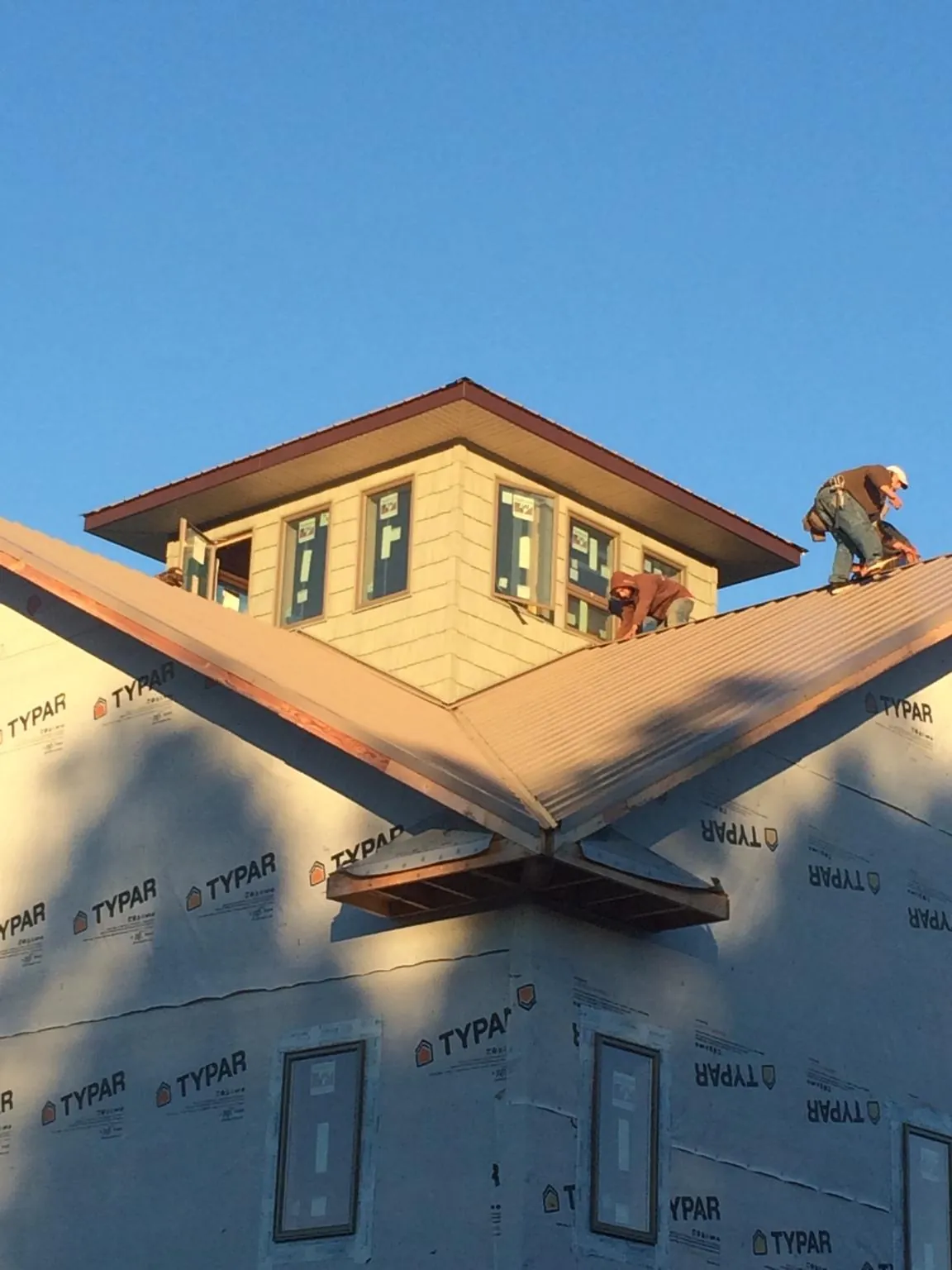 Roofers working around a rooftop cupola on a new metal roof at sunset — Roof Waterproofing in Finley by Roofing Brothers